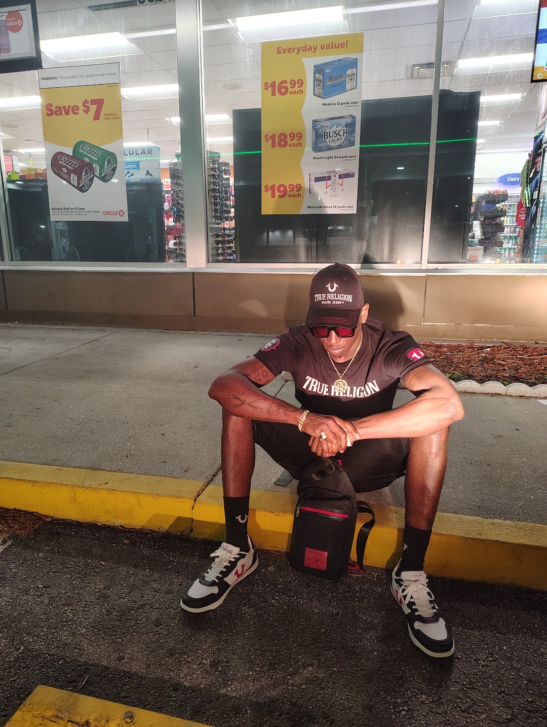 Twan G Young Gutta wearing a black True Religion cap, shirt, socks and sneakers outside at night