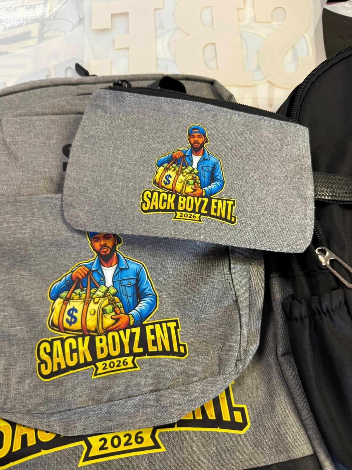 Grey Sack Boyz Entertainment 2026 backpack and matching accessory pouch