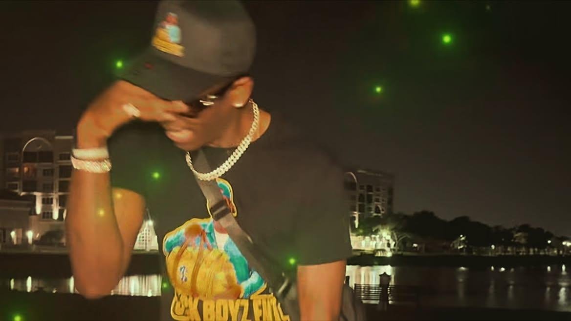 Twan G Young Gutta wearing a black Sack Boyz Entertainment shirt outdoors at night