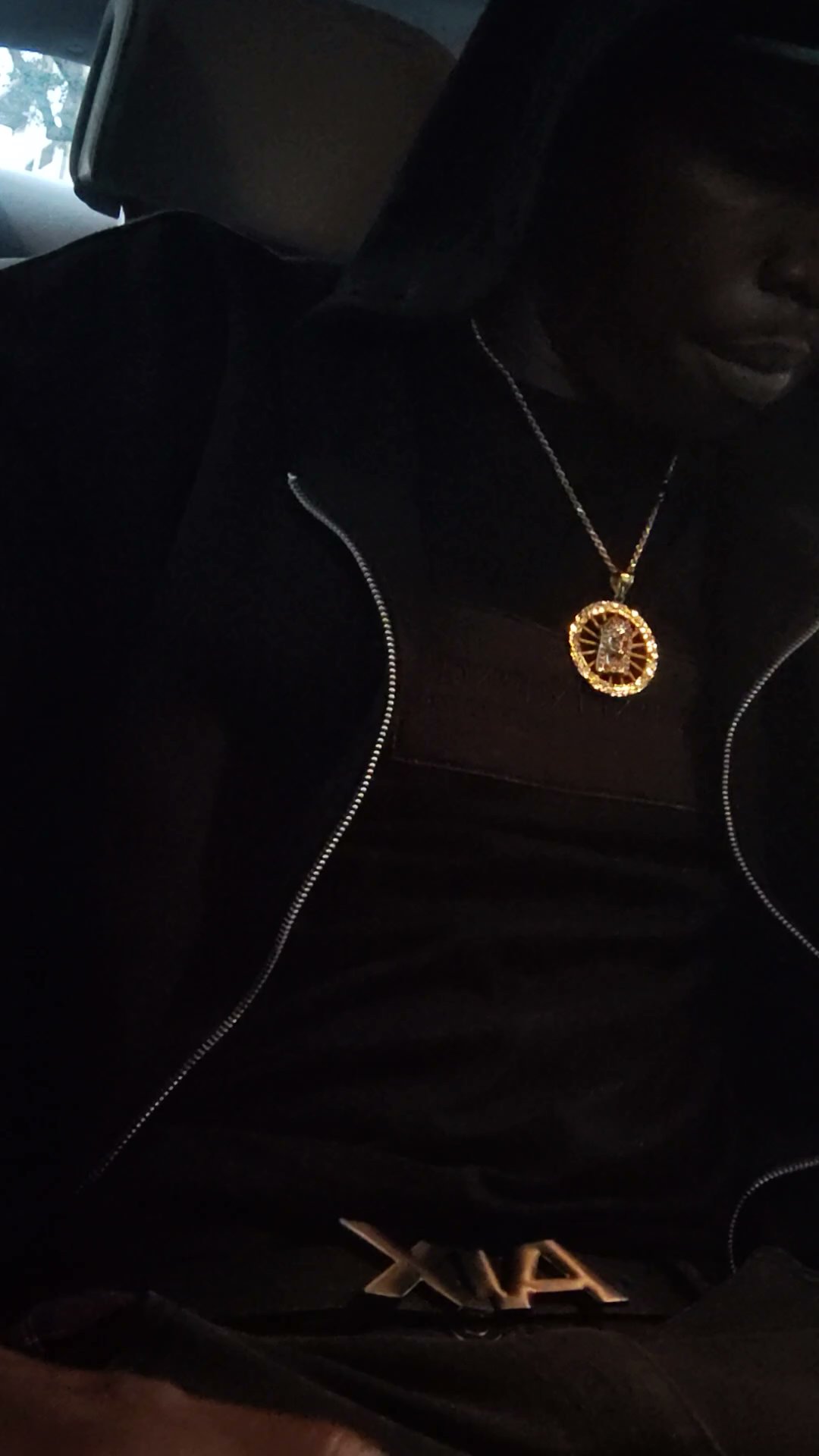 Low-light portrait of Twan G Young Gutta dressed in black with a gold chain
