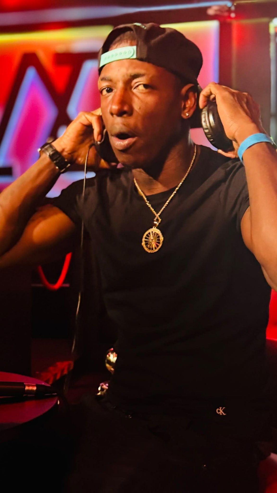 Twan G Young Gutta putting on headphones in a red-lit venue