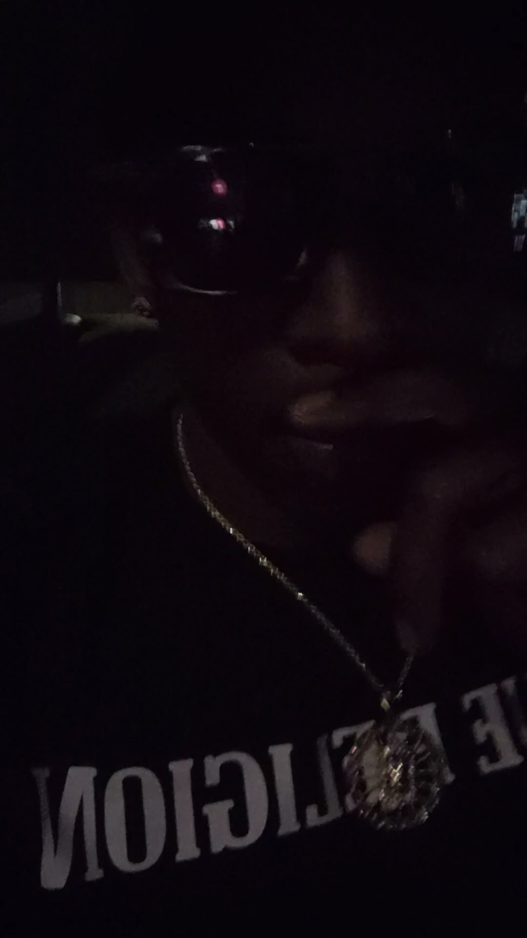 Low-light portrait of Twan G Young Gutta wearing a black True Religion shirt and gold chain