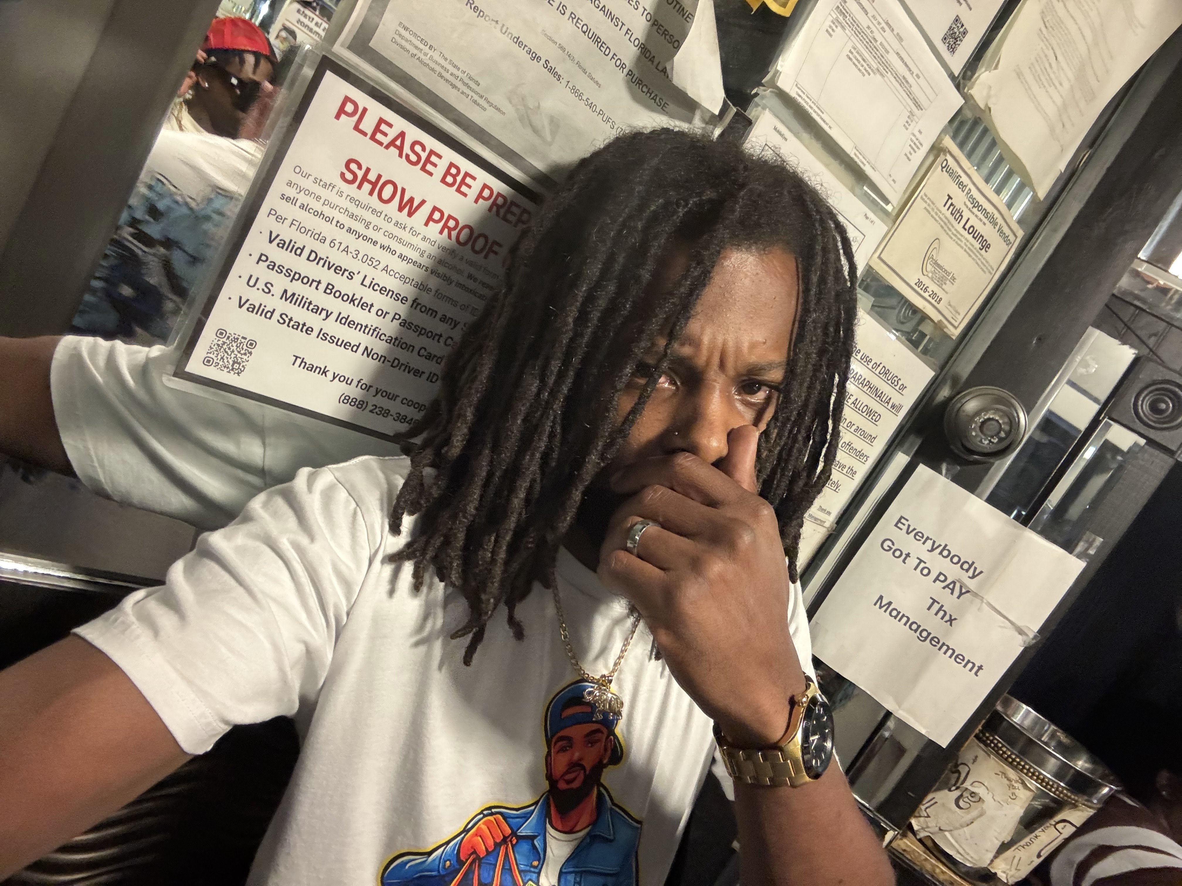 Chevy GC taking a selfie in a white Sack Boyz Entertainment T-shirt while wearing a gold watch